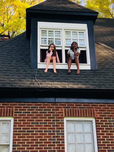 白天，两个女孩坐在白色的双层玻璃窗上